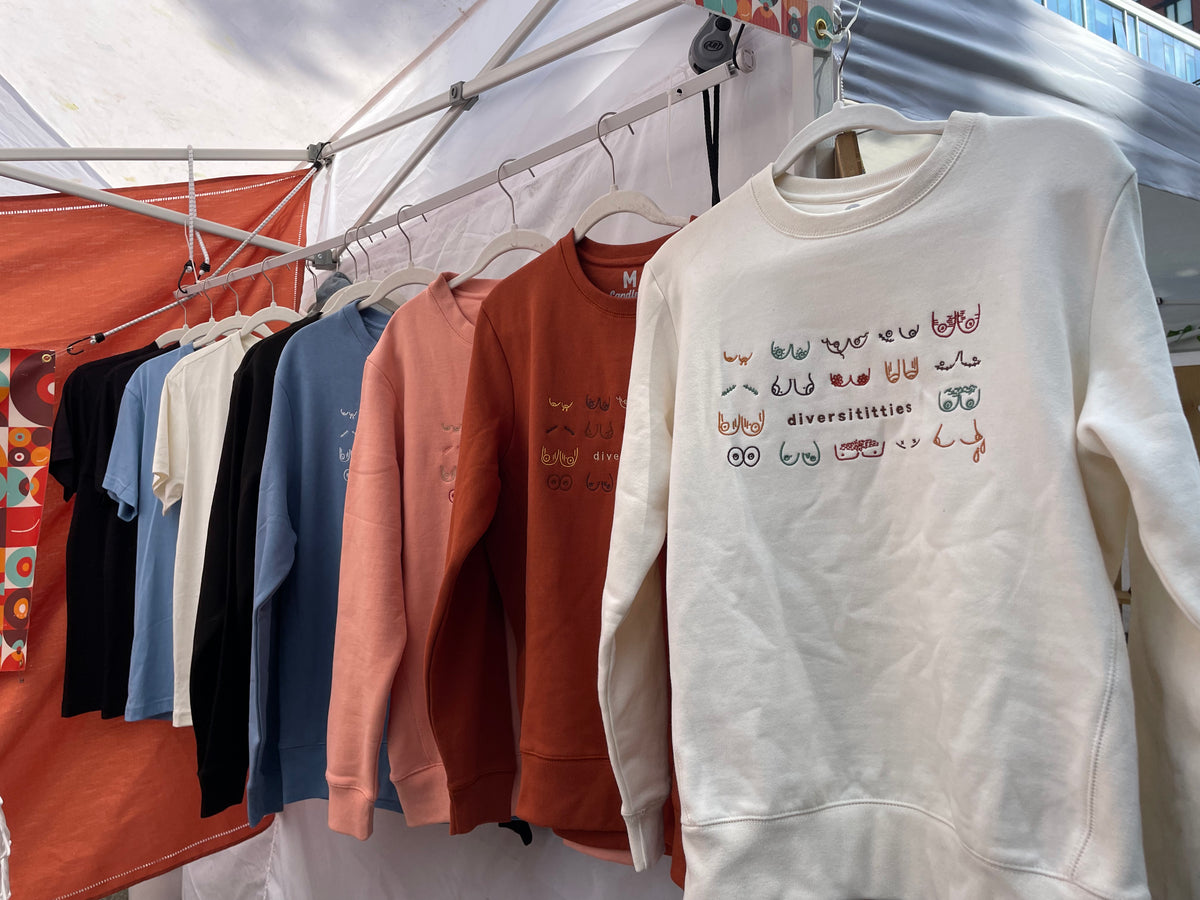 Diversititties sweatshirts hanging up at outdoor market